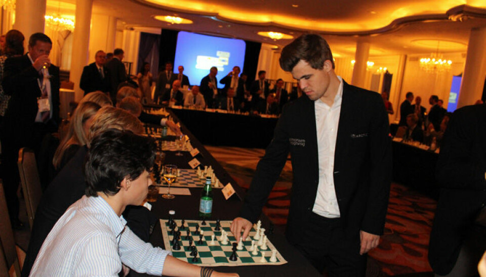 Magnus Carlsen gikk fra bord til bord under seansen på Omni Shoreham hotel. Her flytter han en brikke på brettet til Norges ambassadør Kåre R Aas som for anledningen hadde tatt med seg sønnen Felipe på sitt lag.