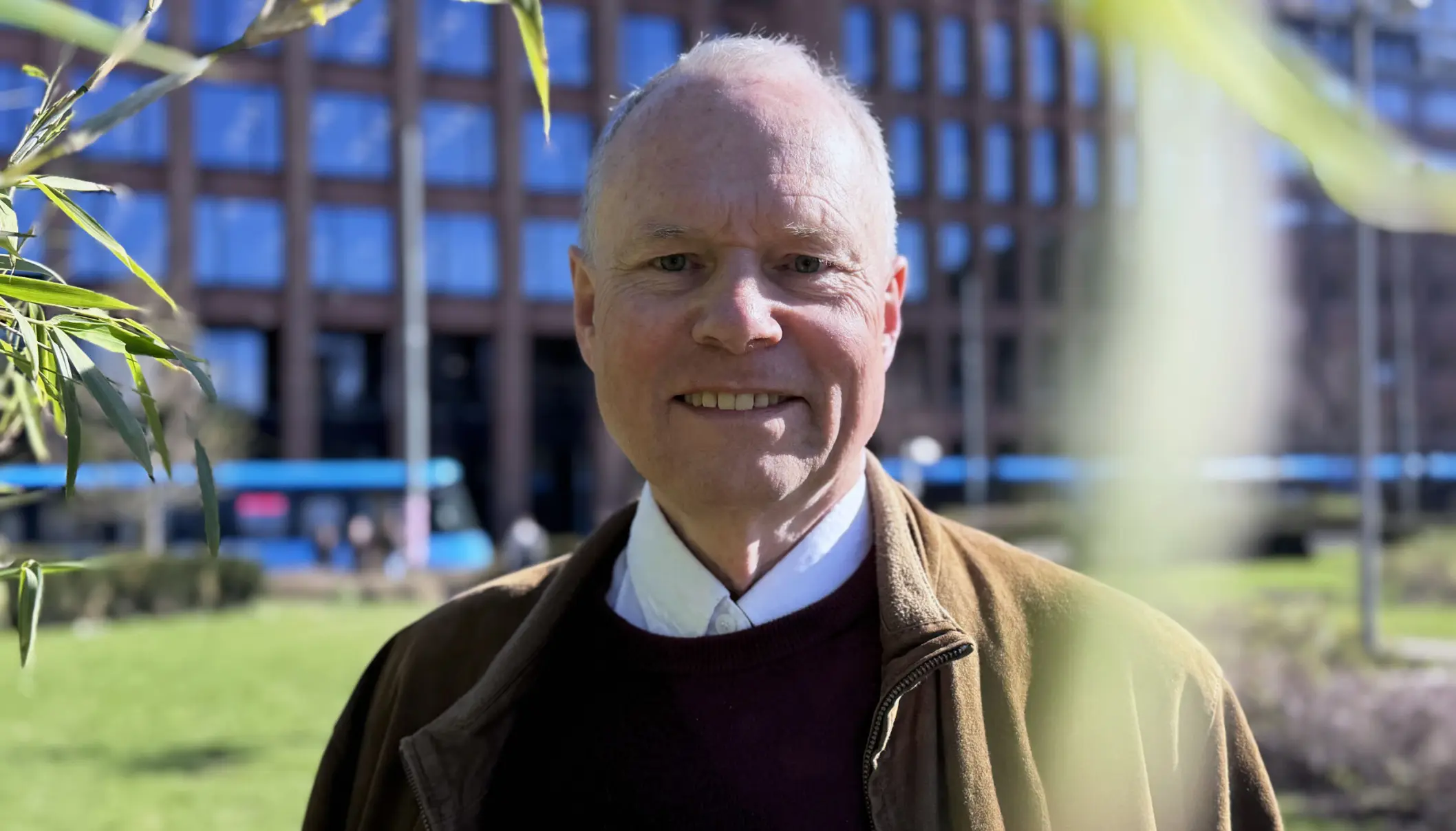 Mann smiler til kameraet ute foran et bygg.
